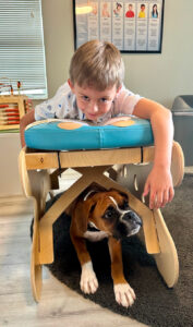 Young Male pediatric patient on pediatric adjustment table with Dublin the companion puppy beneath him